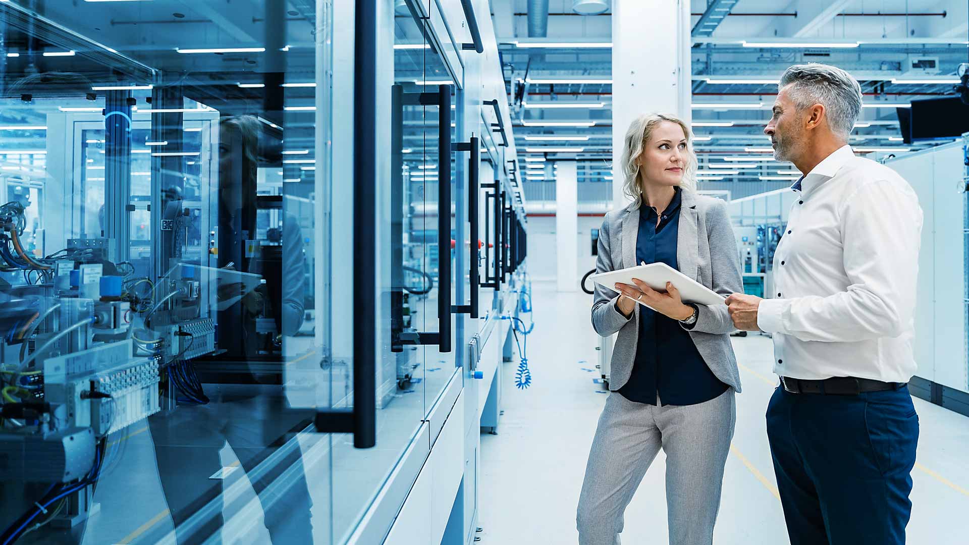 Geschäftsfrau und Geschäftsmann unterhalten sich in einer Industriehalle