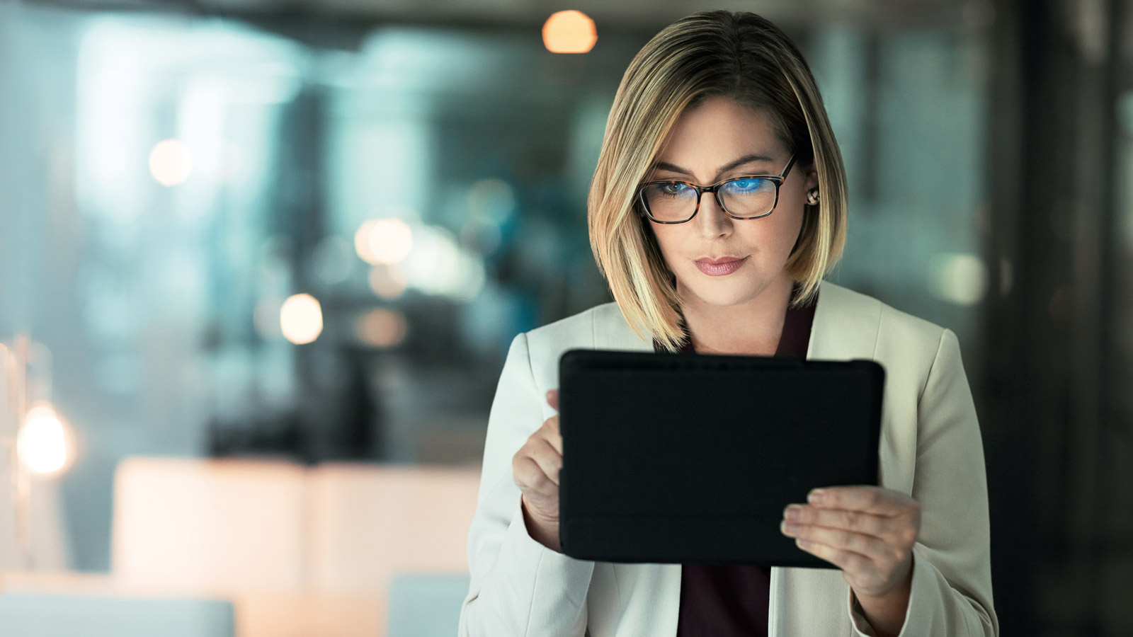 Hübsche Frau mit Brille schaut auf ein Tablet