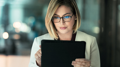 Hübsche Frau mit Brille schaut auf ein Tablet